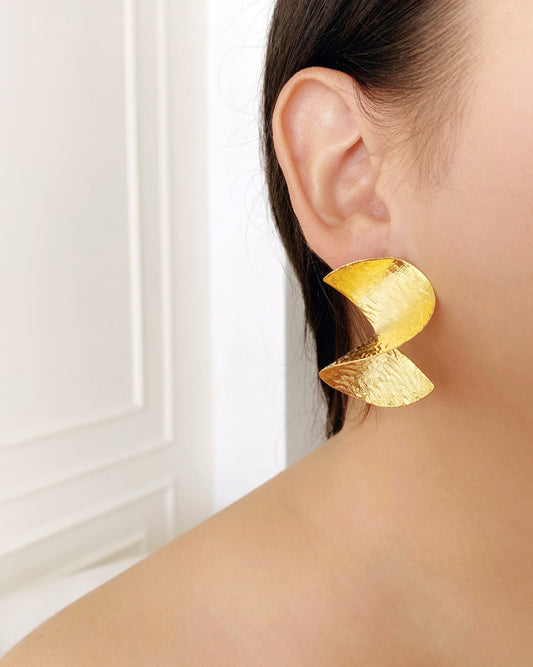 Aretes Topos ondulados de Florel Accesorios en uso, resaltando movimiento y brillo sobre la piel.